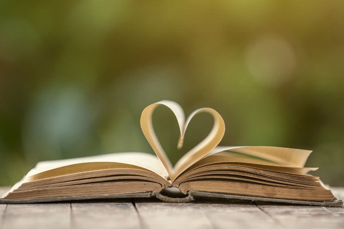 An image of an open book which has the middle pages arranged in a shape of a heart