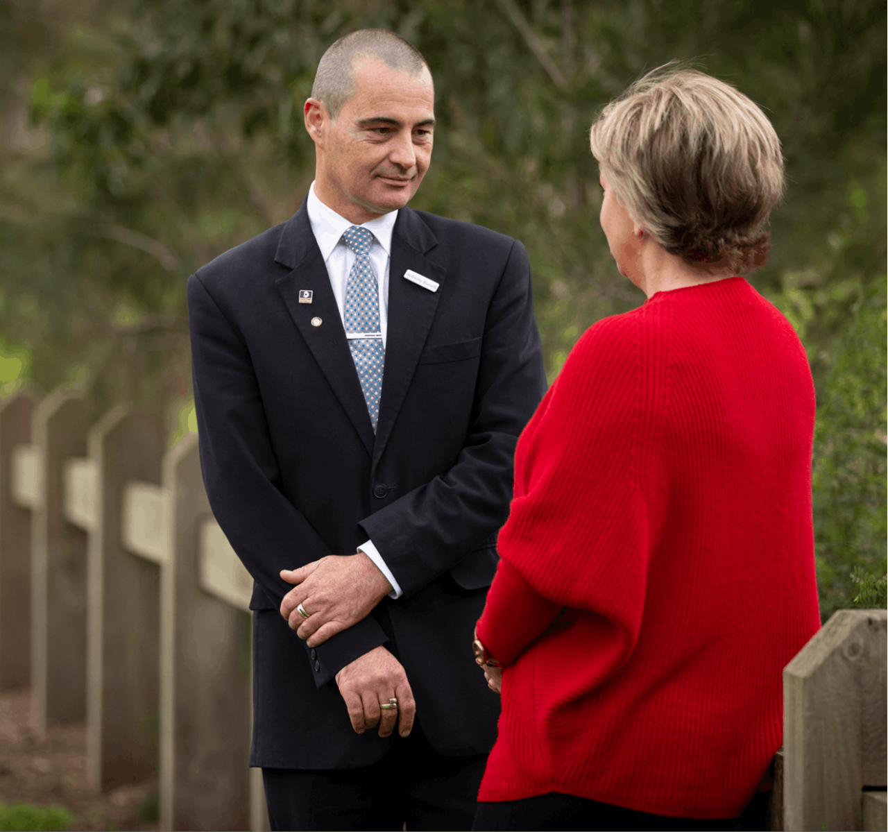 An image of two indviduals with one man in a uniform and a woman with a red sweater. They are facing each other and seems are discussing something
