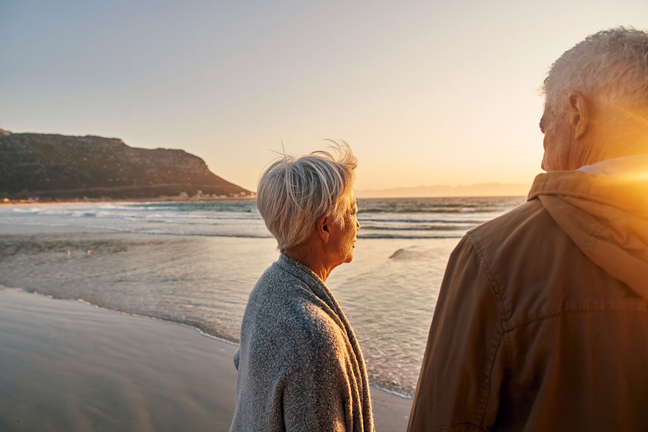 A man and a woman looking off into the sunset at the beach